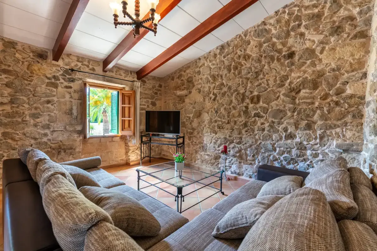 A stone-walled living room with seating around a glass coffee table.