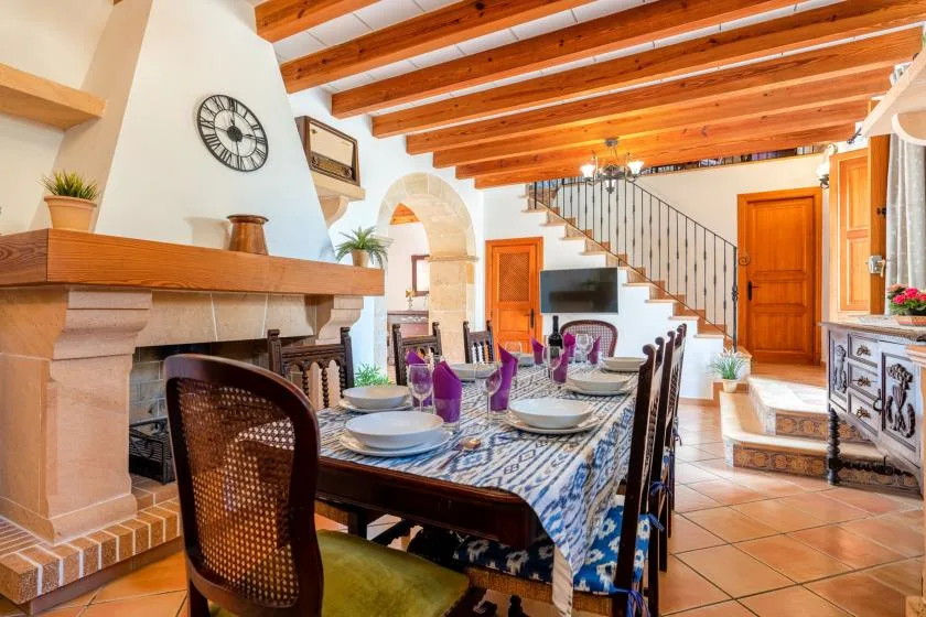 A dining room with a set table beside a fireplace and staircase.