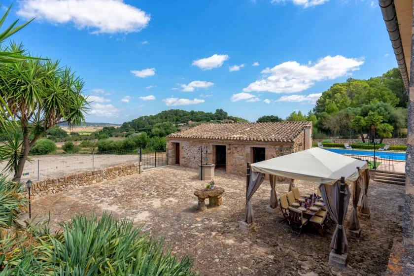A stone courtyard features a shaded dining area and a small outbuilding.