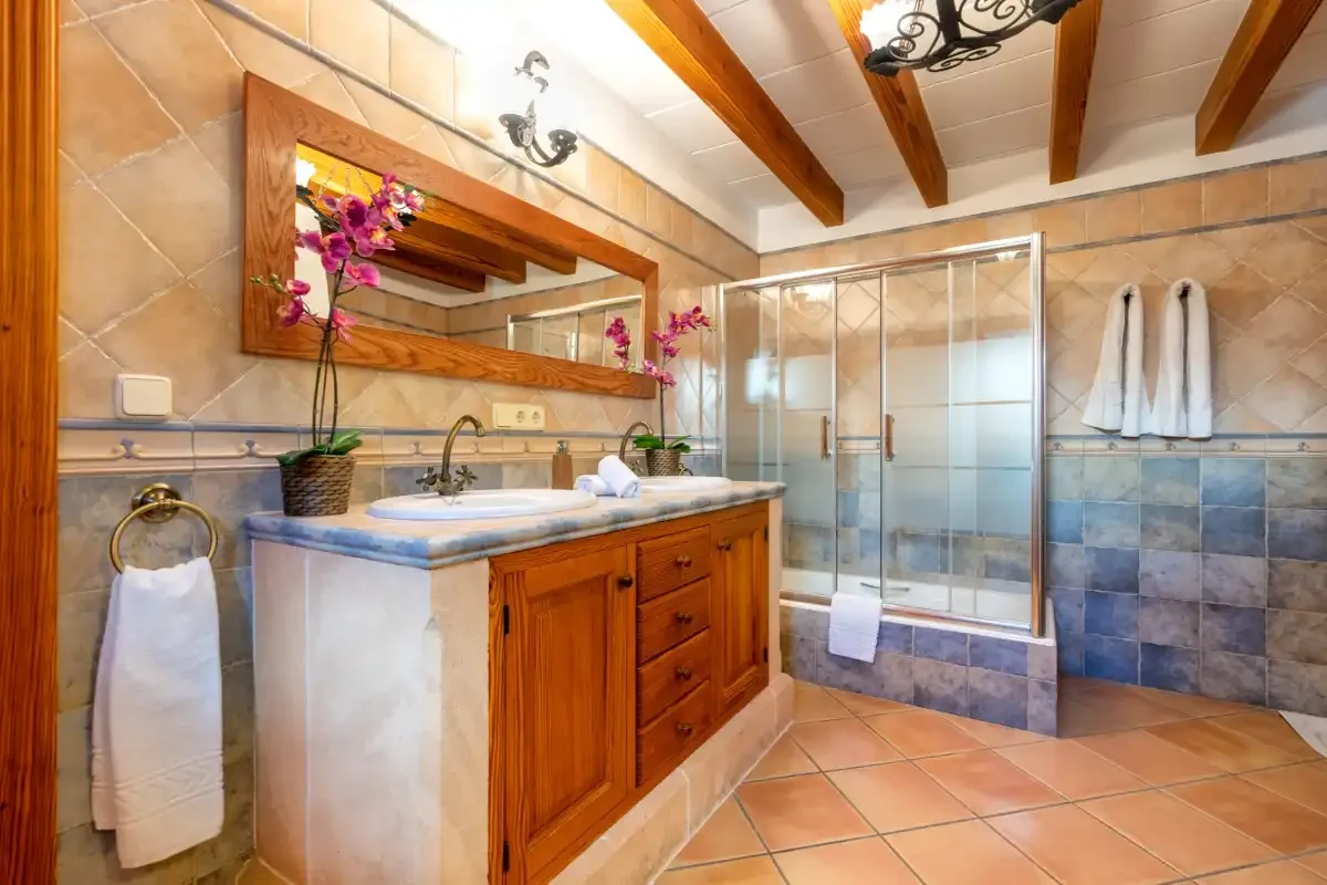 A bathroom with a wooden vanity, sink, and glass shower.