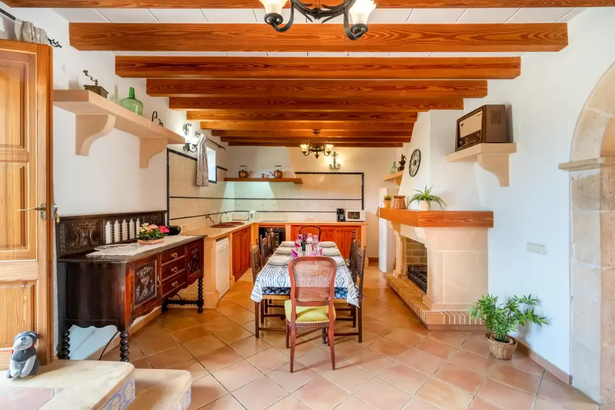 A dining area with a long table and wooden ceiling beams.