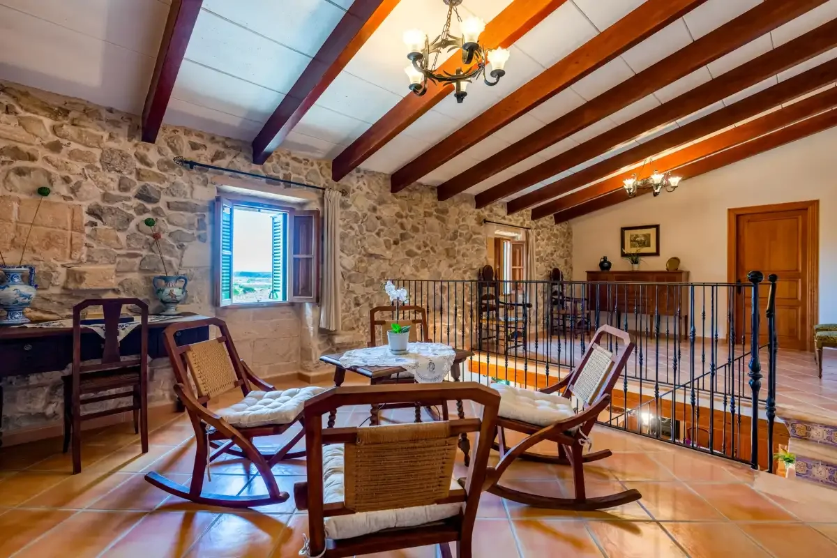 A rustic living room with seating around a small table and a black railing.