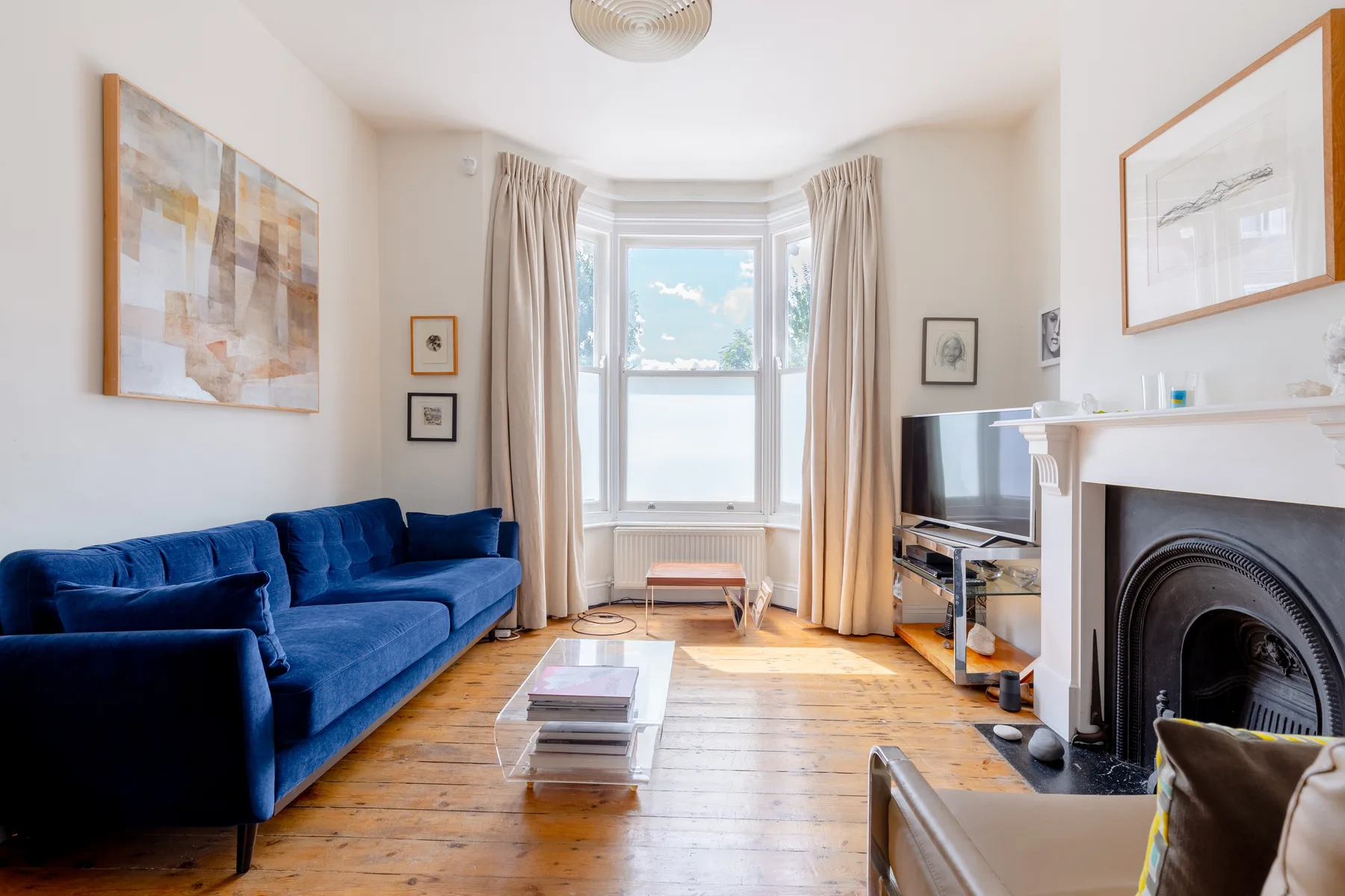 Una sala luminosa con asientos azules, una ventana mirador y una chimenea.