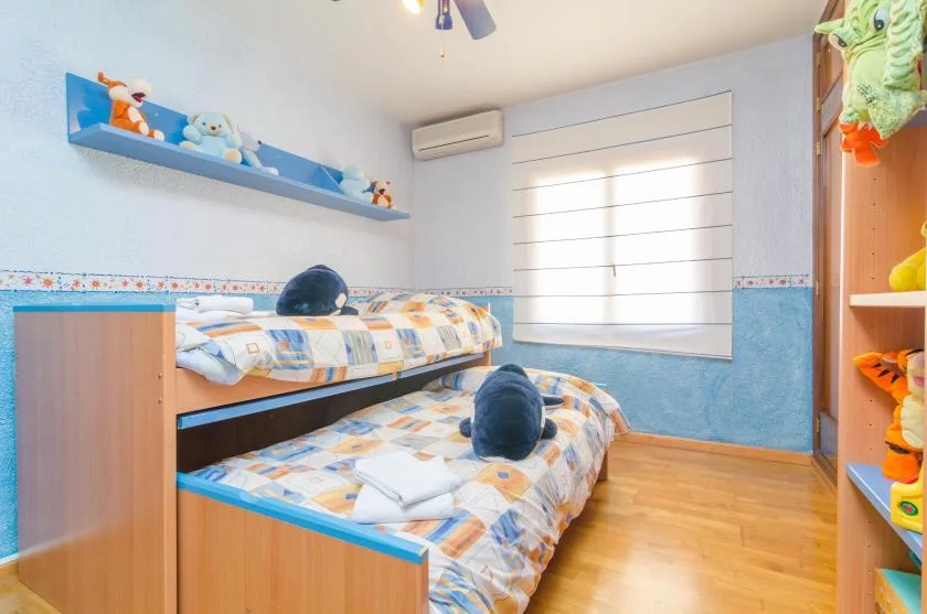 A bright bedroom with two beds, colorful bedding, and a window.