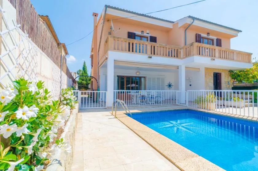 A two-story house stands beside a bright blue swimming pool.