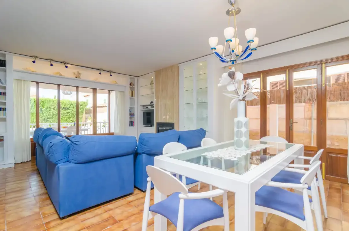 A bright living and dining area with blue seating and a glass-topped table.