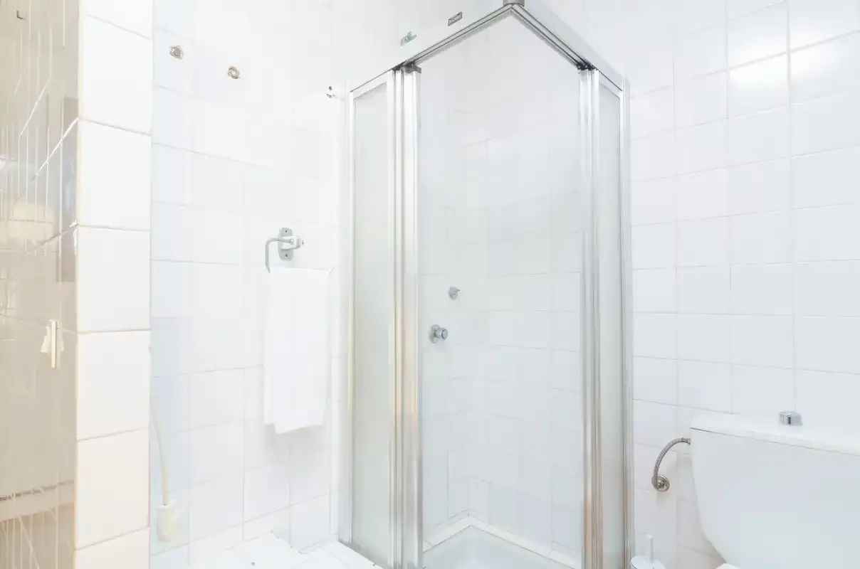 A tiled bathroom with a glass shower and wall-mounted fixtures.