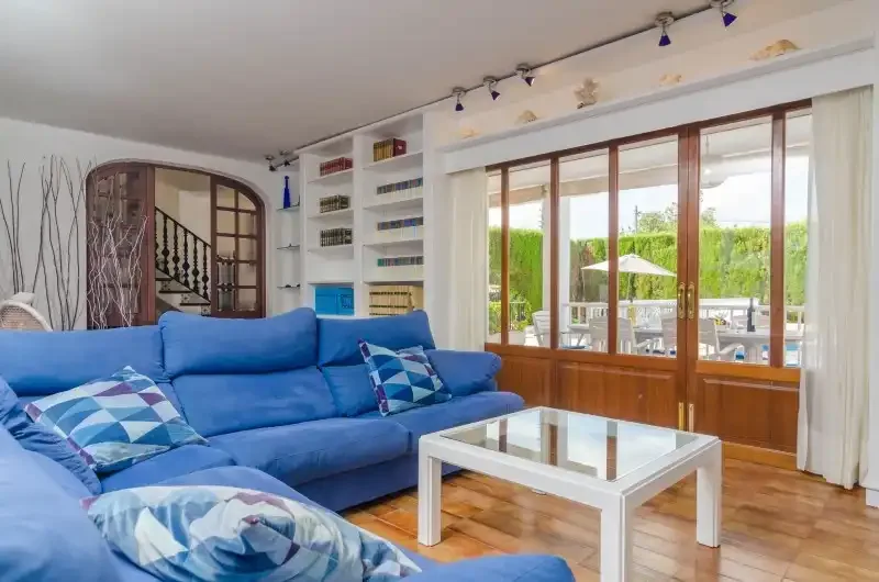 A bright living room with blue seating and glass doors opening onto a patio.