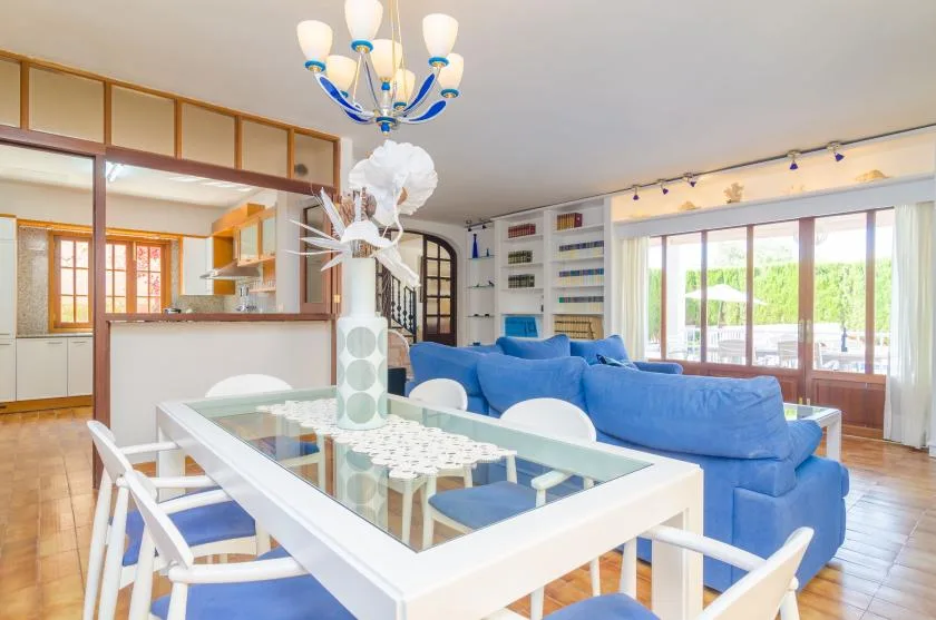 A bright living and dining area with blue seating and large windows.