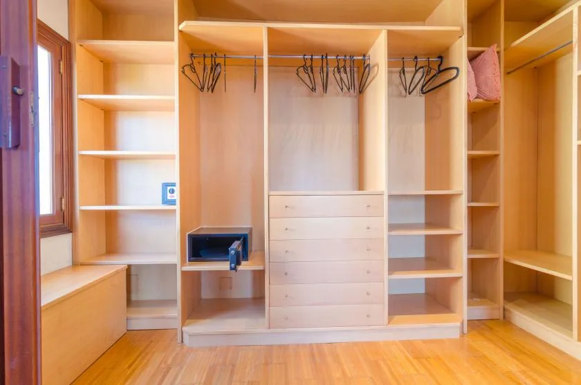 A spacious wooden closet with open shelving, hanging rails, and drawers.
