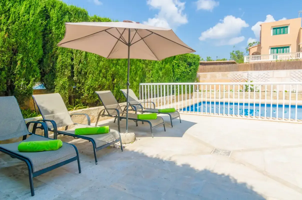 A poolside patio with lounge seating and a large shade umbrella.