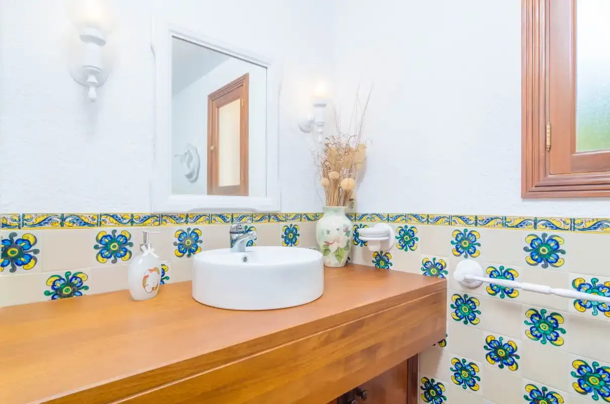 A bathroom vanity with a white basin sits beneath a wall mirror.