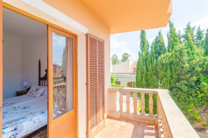 A small balcony with tiled flooring and a view of trees.