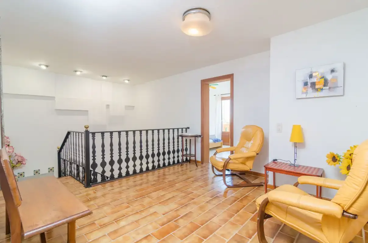 A bright sitting area with yellow seating and a black railing overlooking the lower level.