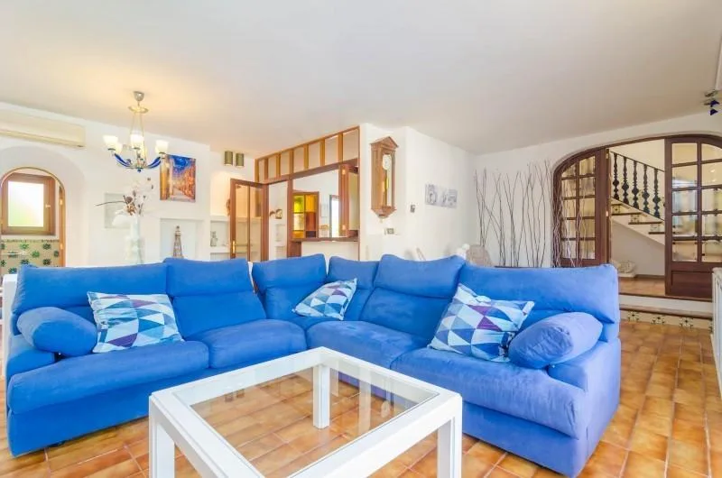 A bright living room with blue seating and a glass-top coffee table.