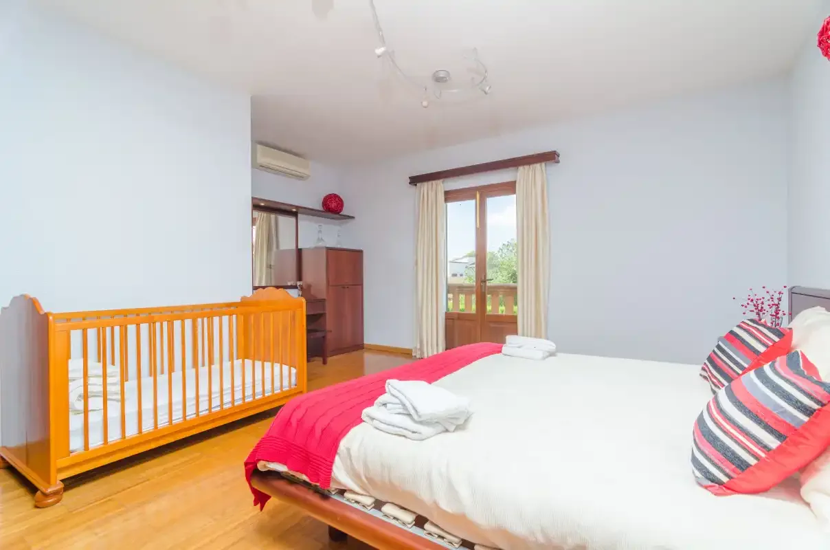 A bedroom with a bed and a wooden crib beside it.