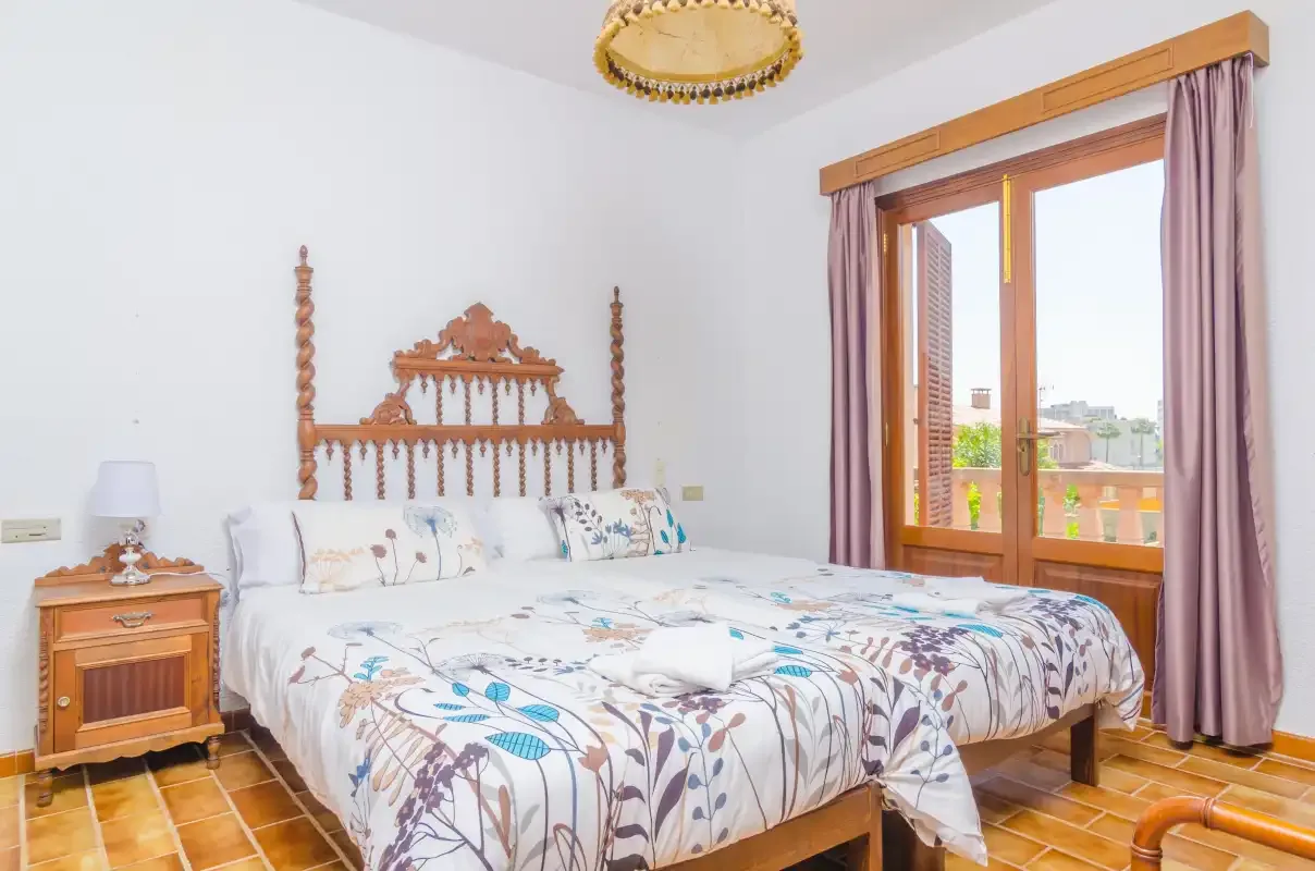A bedroom with a carved wooden bed and a large window overlooking the outdoors.