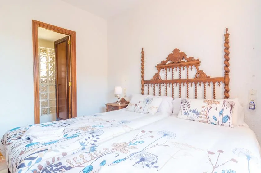 A bedroom with a carved wooden headboard and floral bedding.