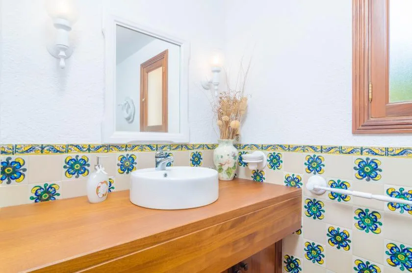 A bathroom vanity with a white sink and colorful patterned tile.