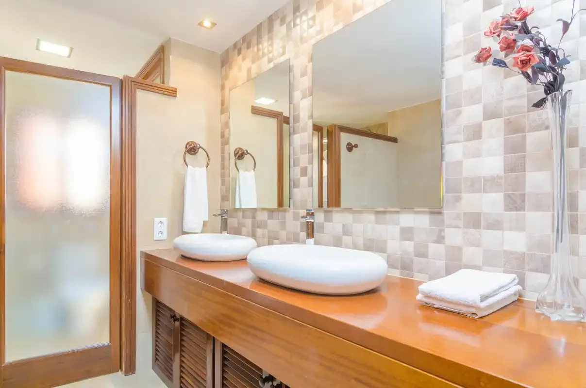 A bathroom vanity with two sinks, a large mirror, and folded towels.