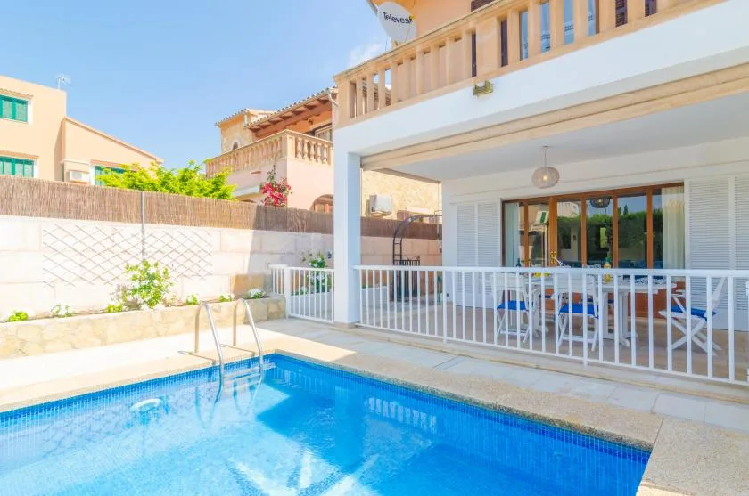 A swimming pool beside a covered patio with white railings.