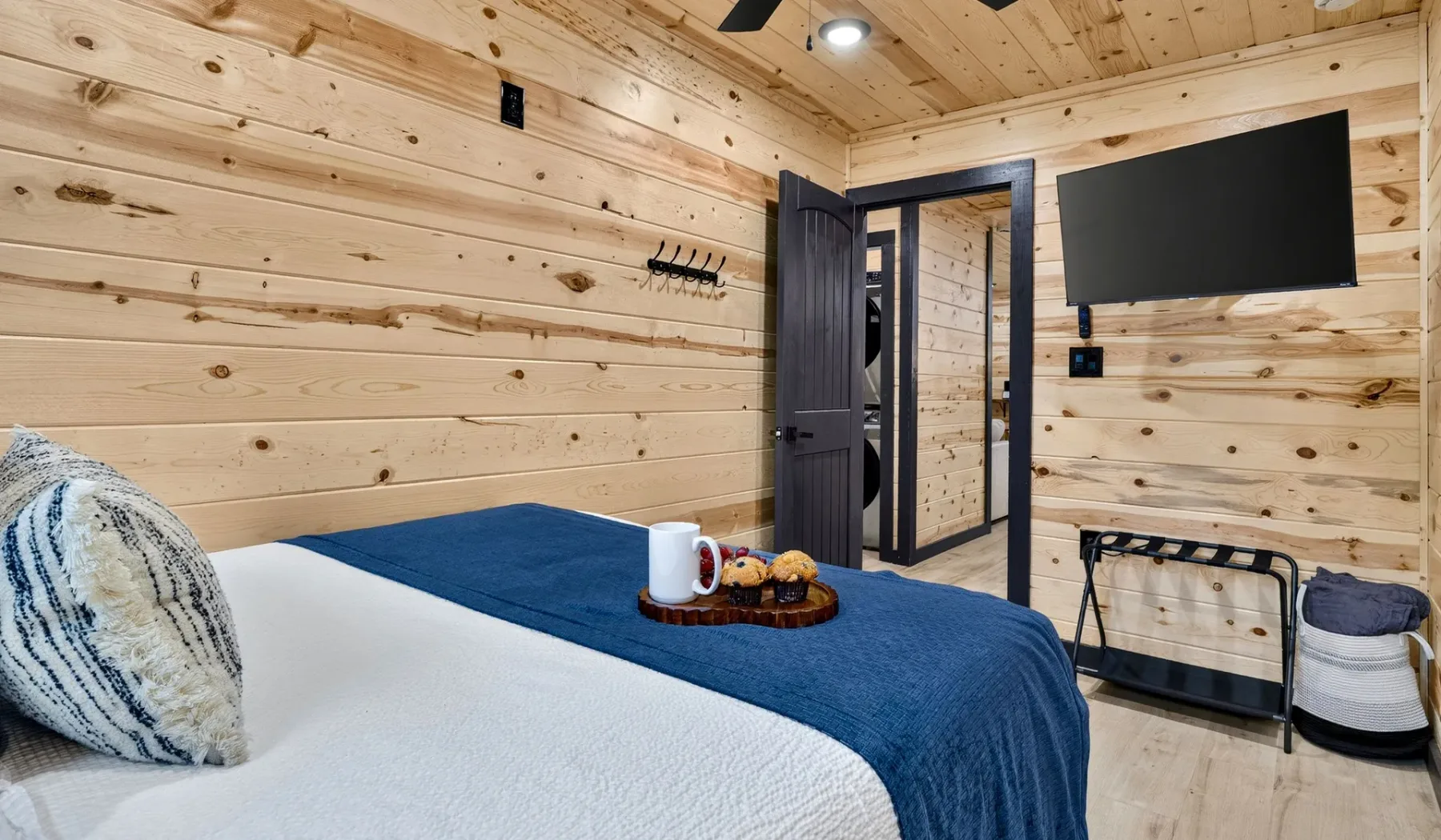 A bedroom with a bed, blue bedding, and a wall-mounted television.