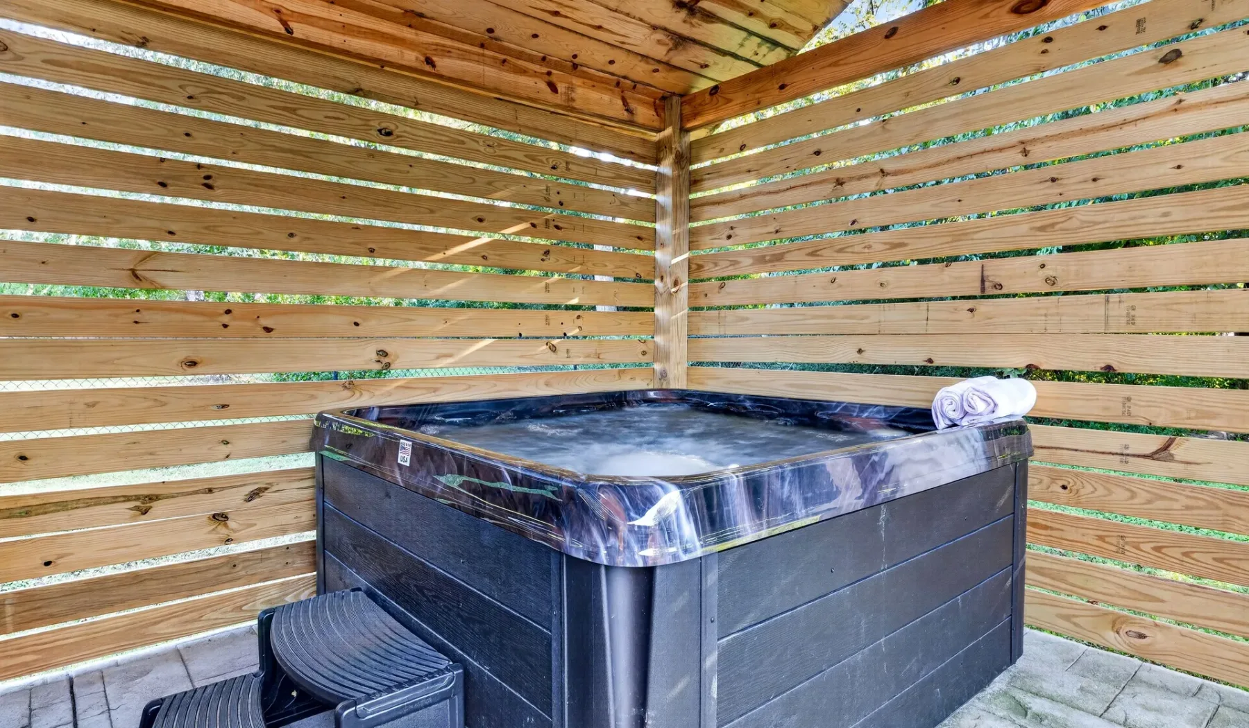 A hot tub sits in a wooden-slat enclosure.