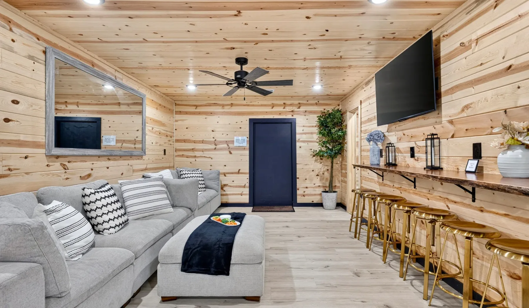 A wood-paneled living room with a sectional seating area and a bar counter.