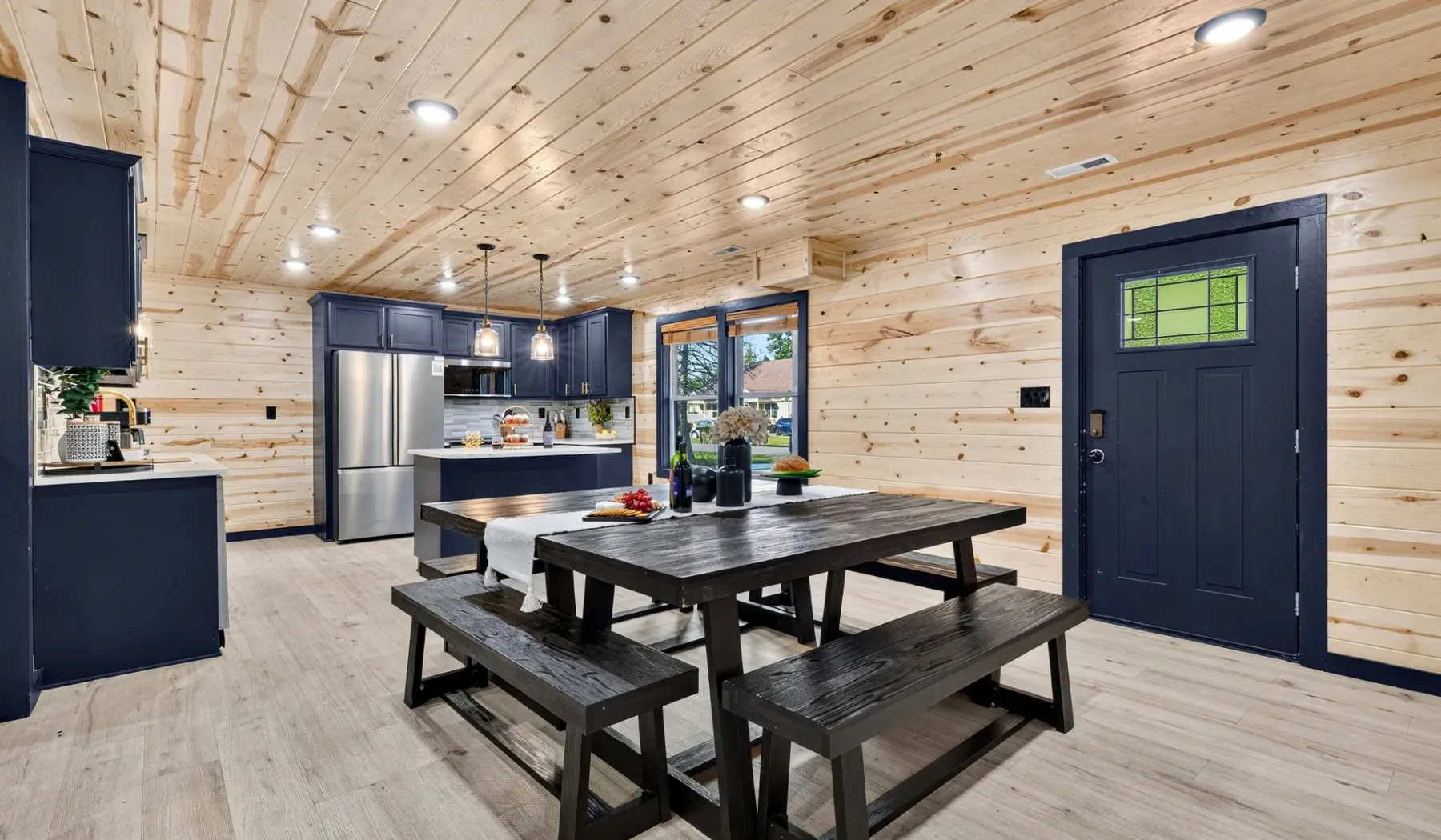A wood-paneled kitchen and dining area with a large table and dark cabinetry.