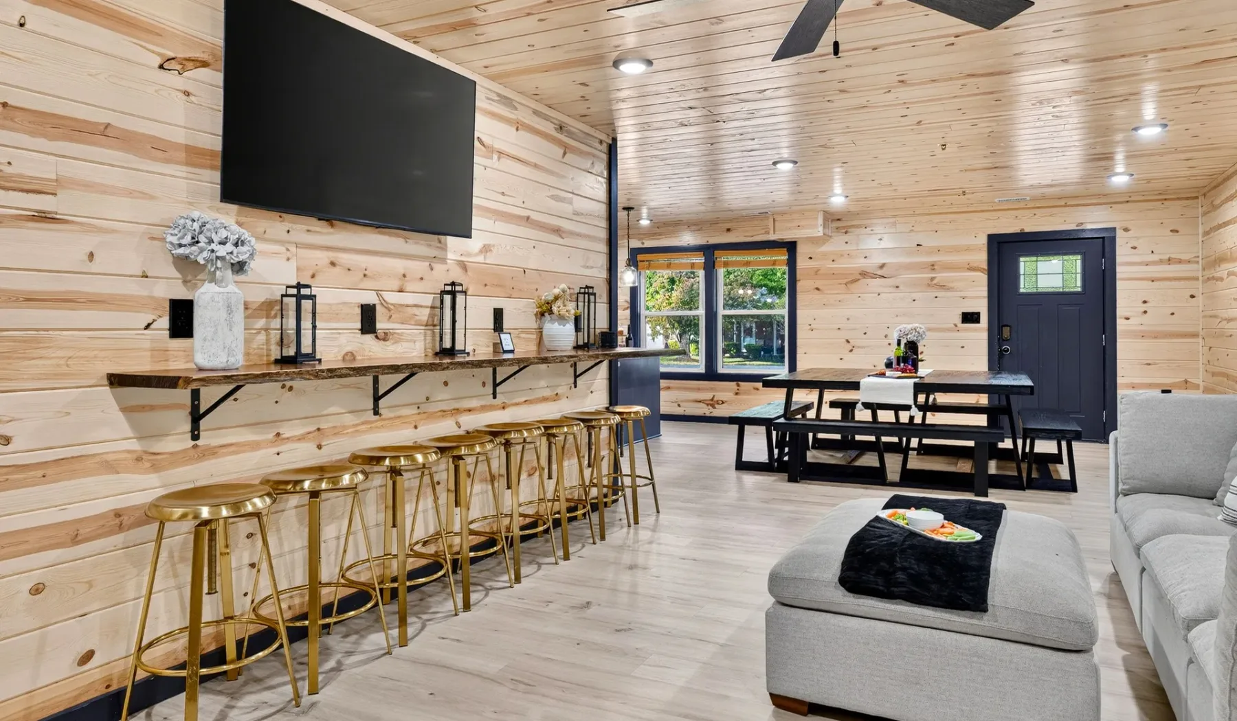 A wood-paneled open room with a long counter, dining table, and seating area.