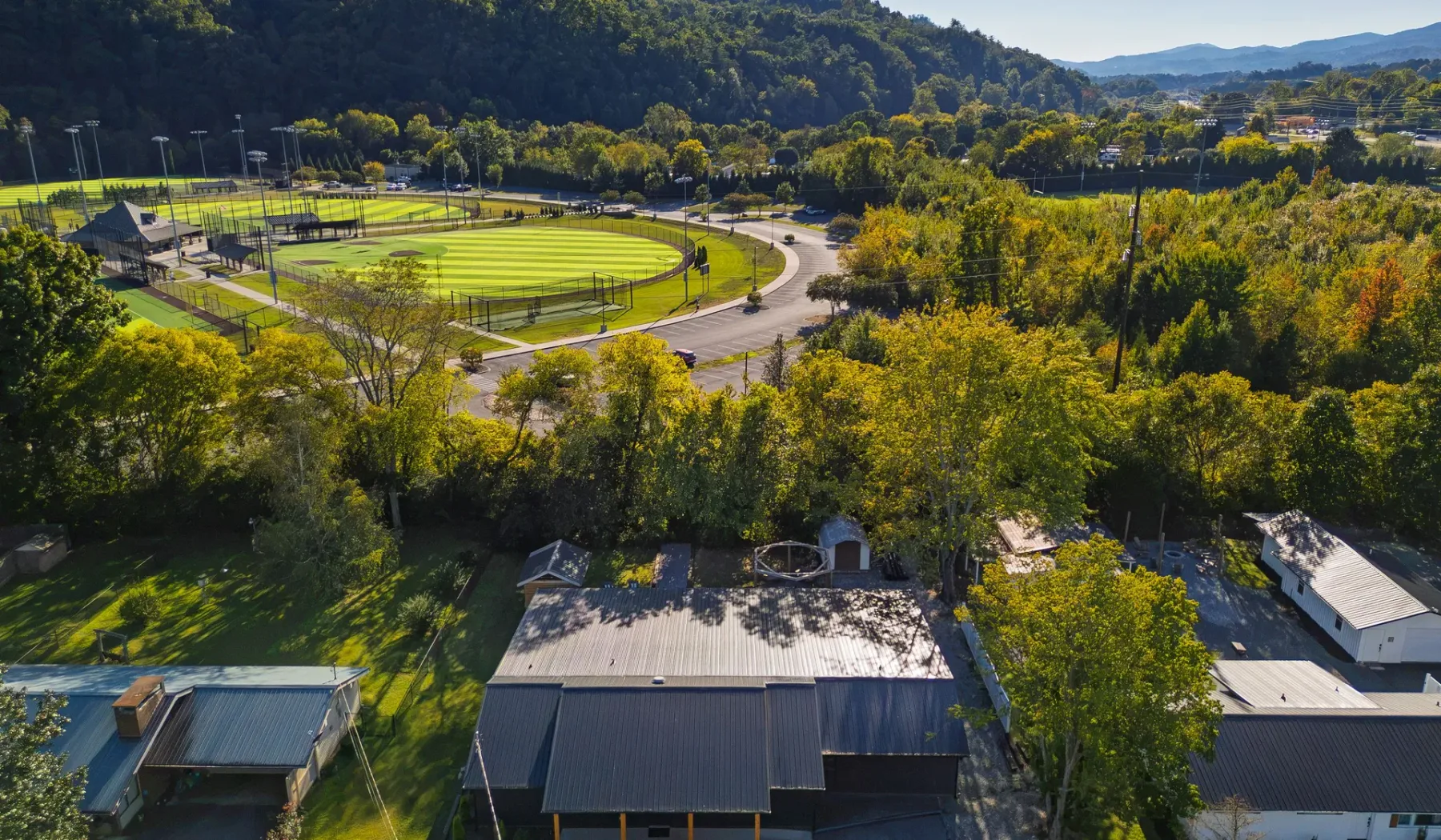 An aerial view of a sports complex with green fields surrounded by trees.