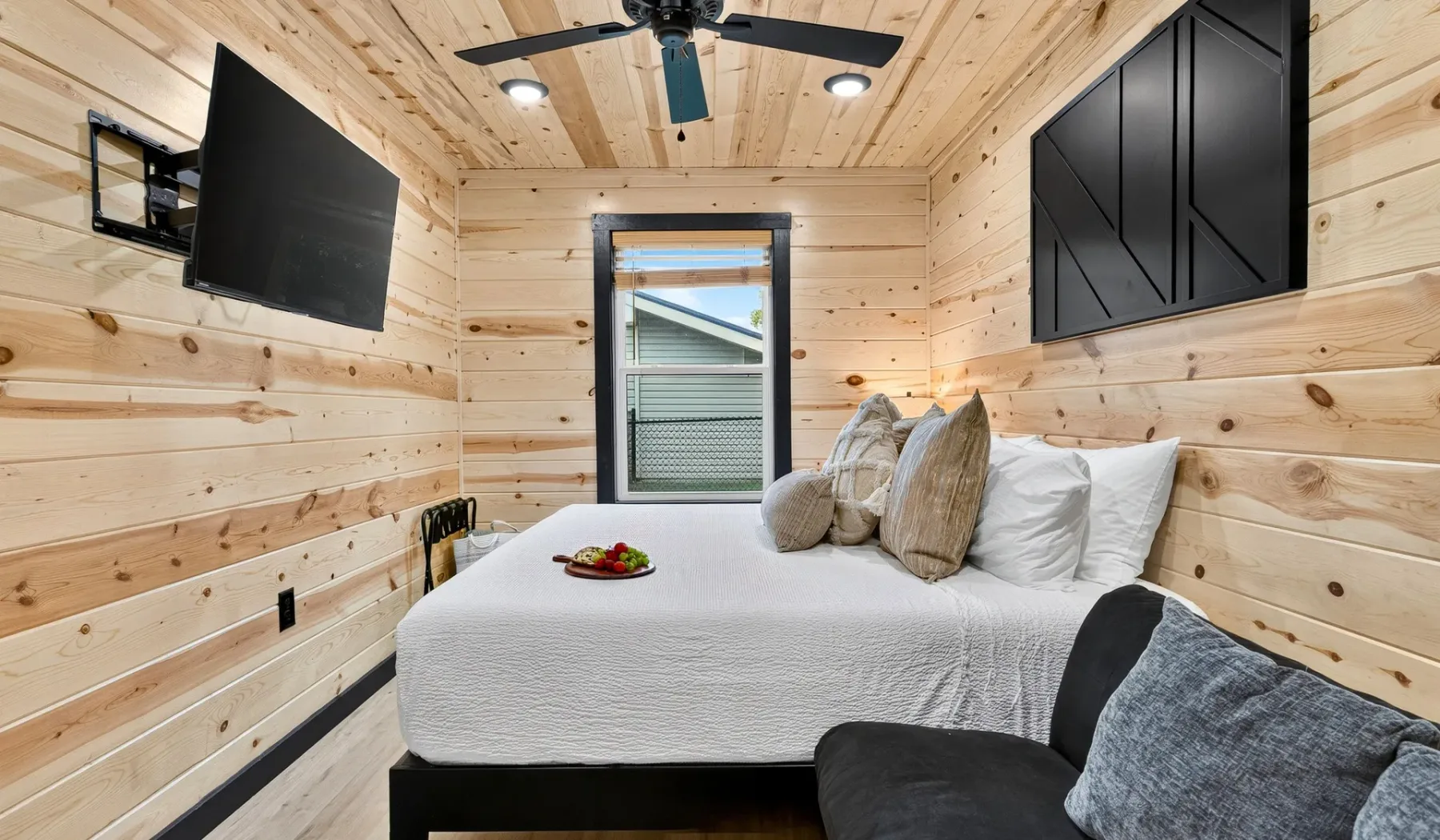 A bedroom with a bed, pillows, and light wood-paneled walls.