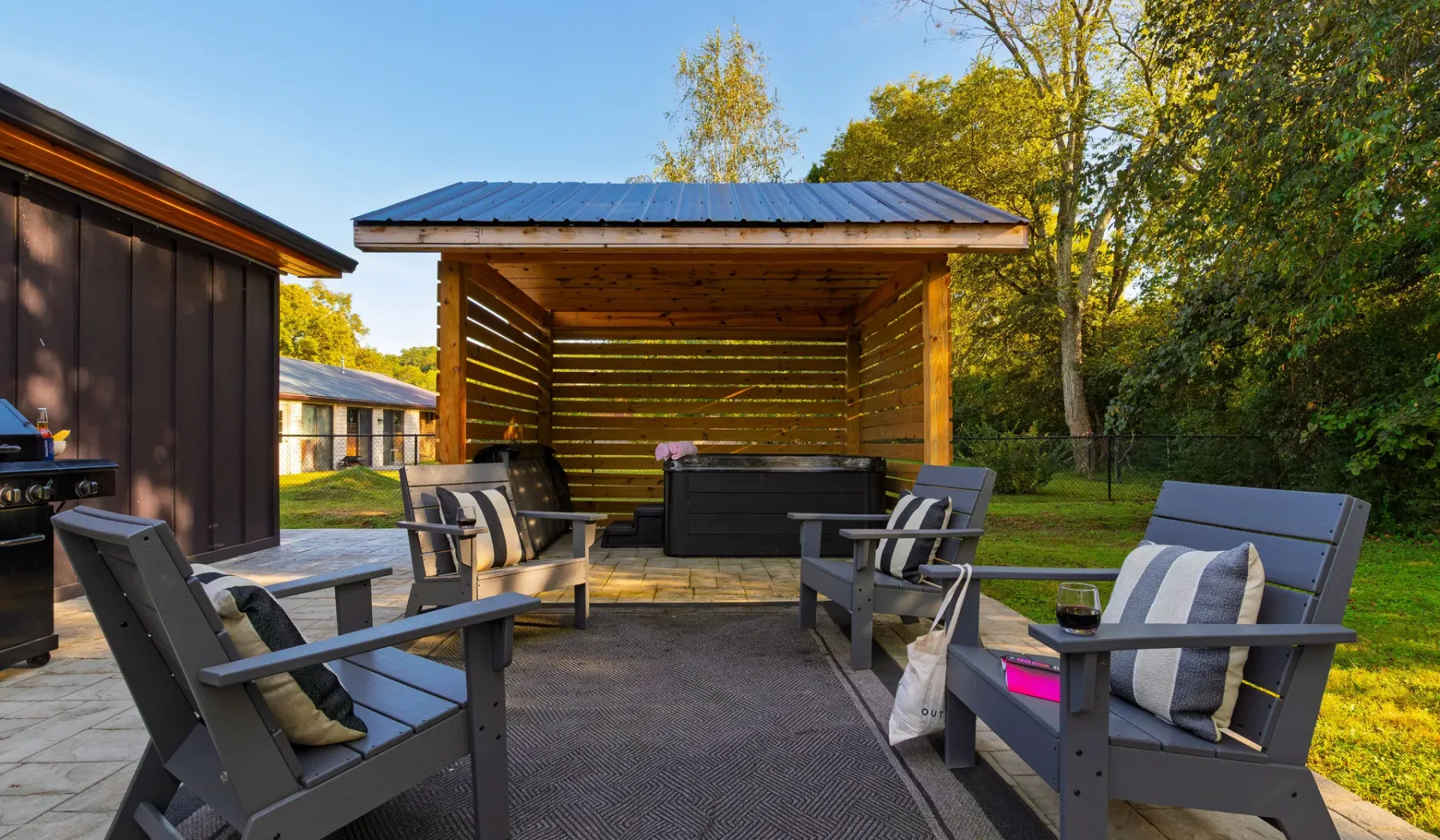 An outdoor seating area faces a covered wooden shelter in a garden.