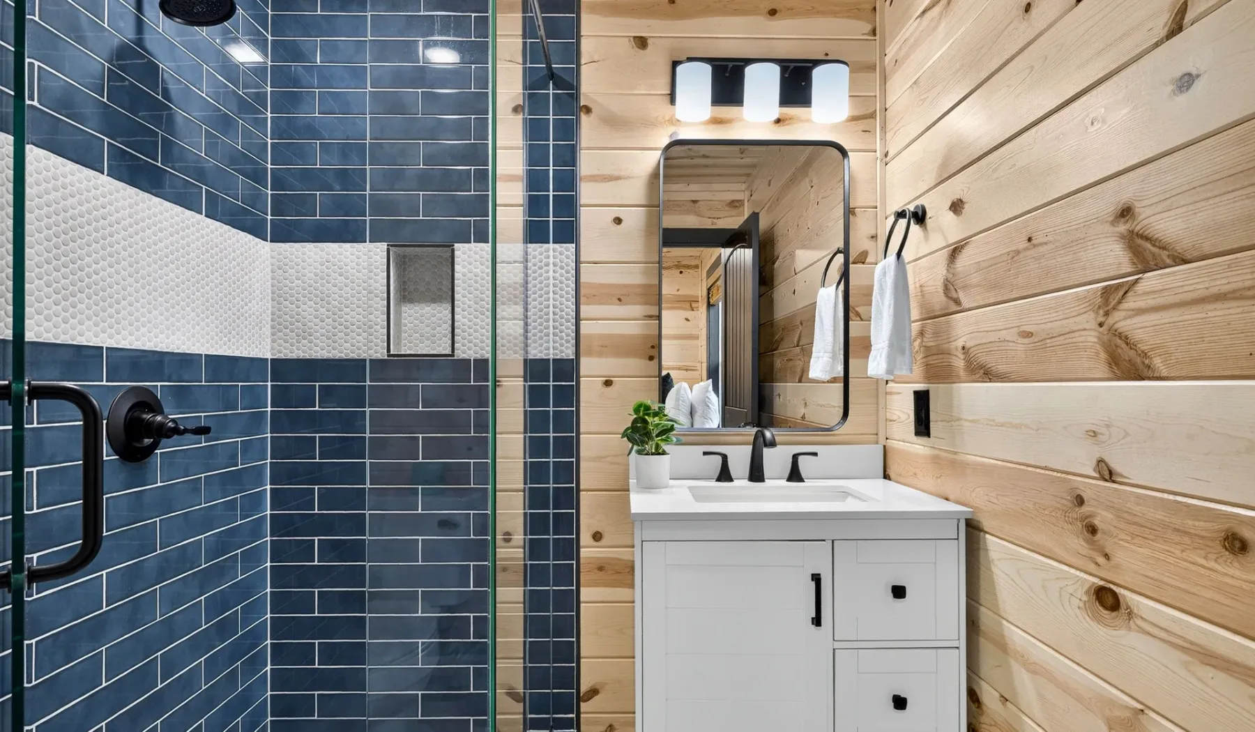 A bathroom with a tiled shower and a white vanity beneath a mirror.