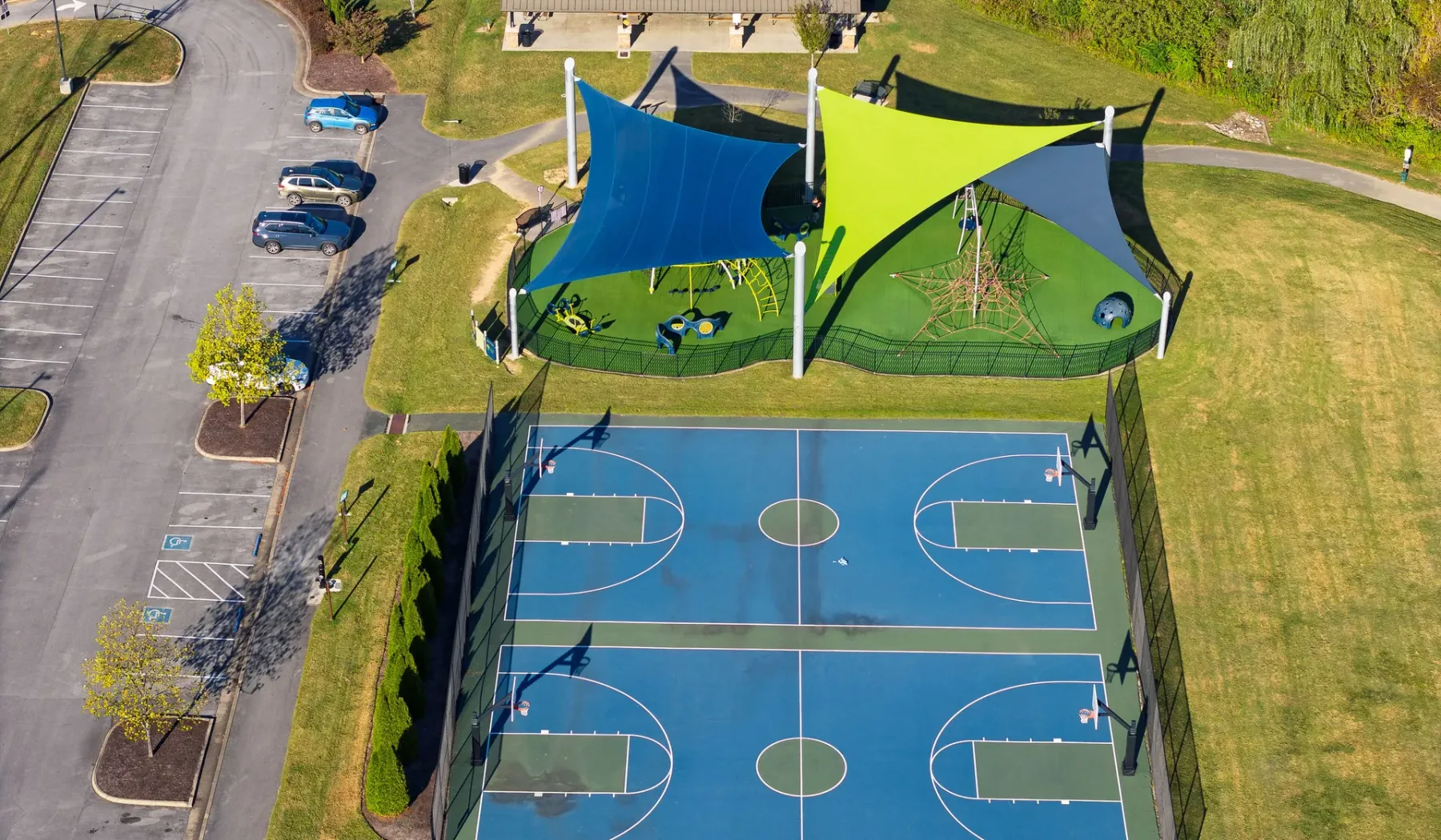 Aerial view of outdoor basketball courts beside a shaded play area.