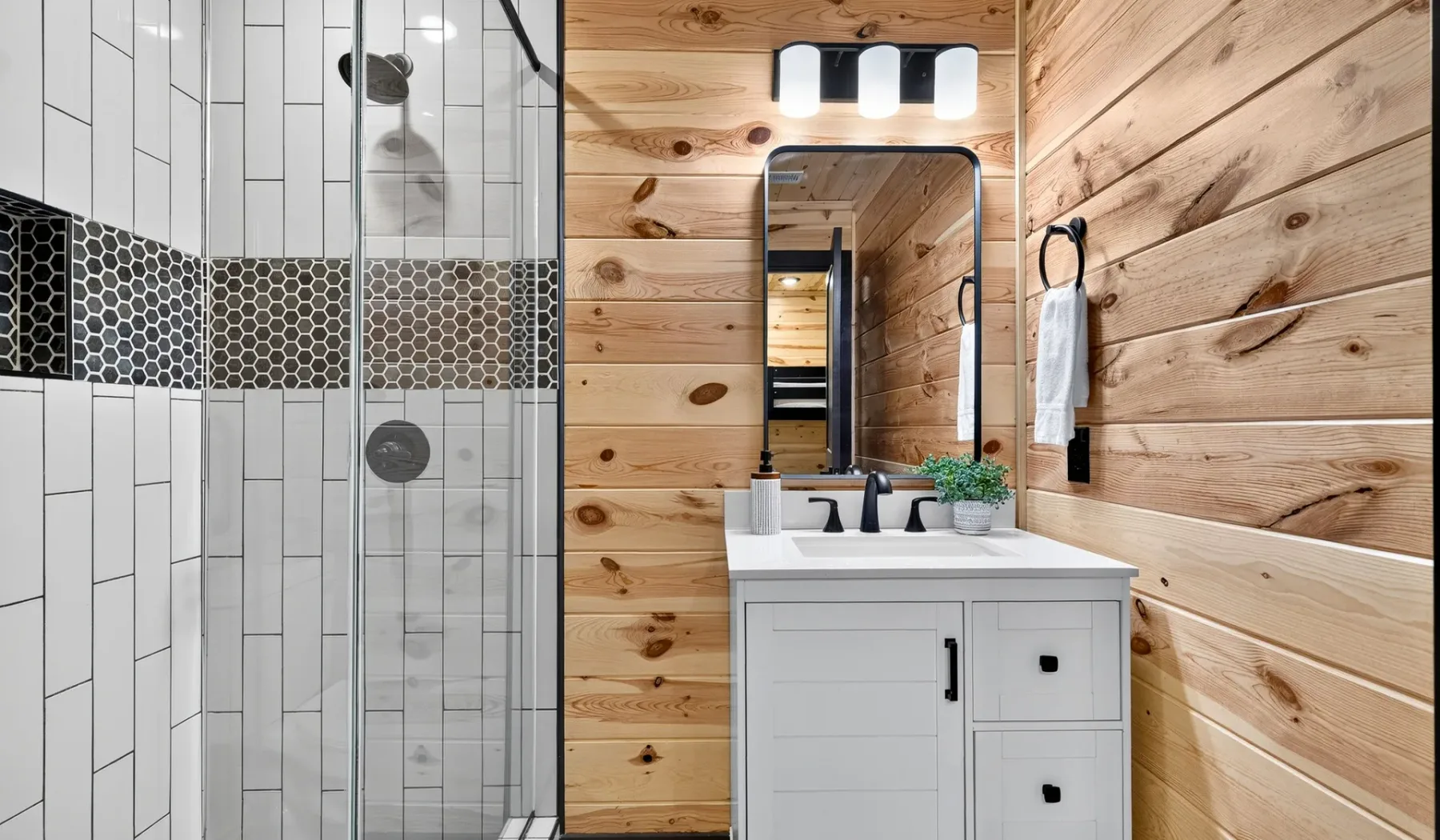 A bathroom with a glass shower beside a vanity and mirror.