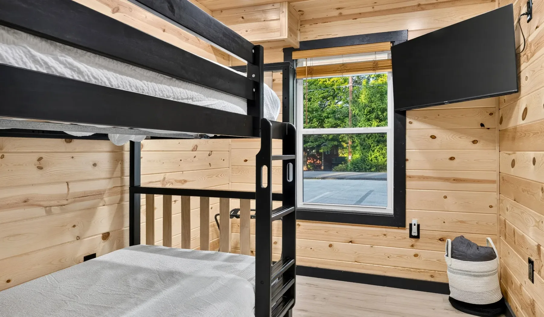 A wood-paneled bedroom with bunk beds and a window overlooking trees.