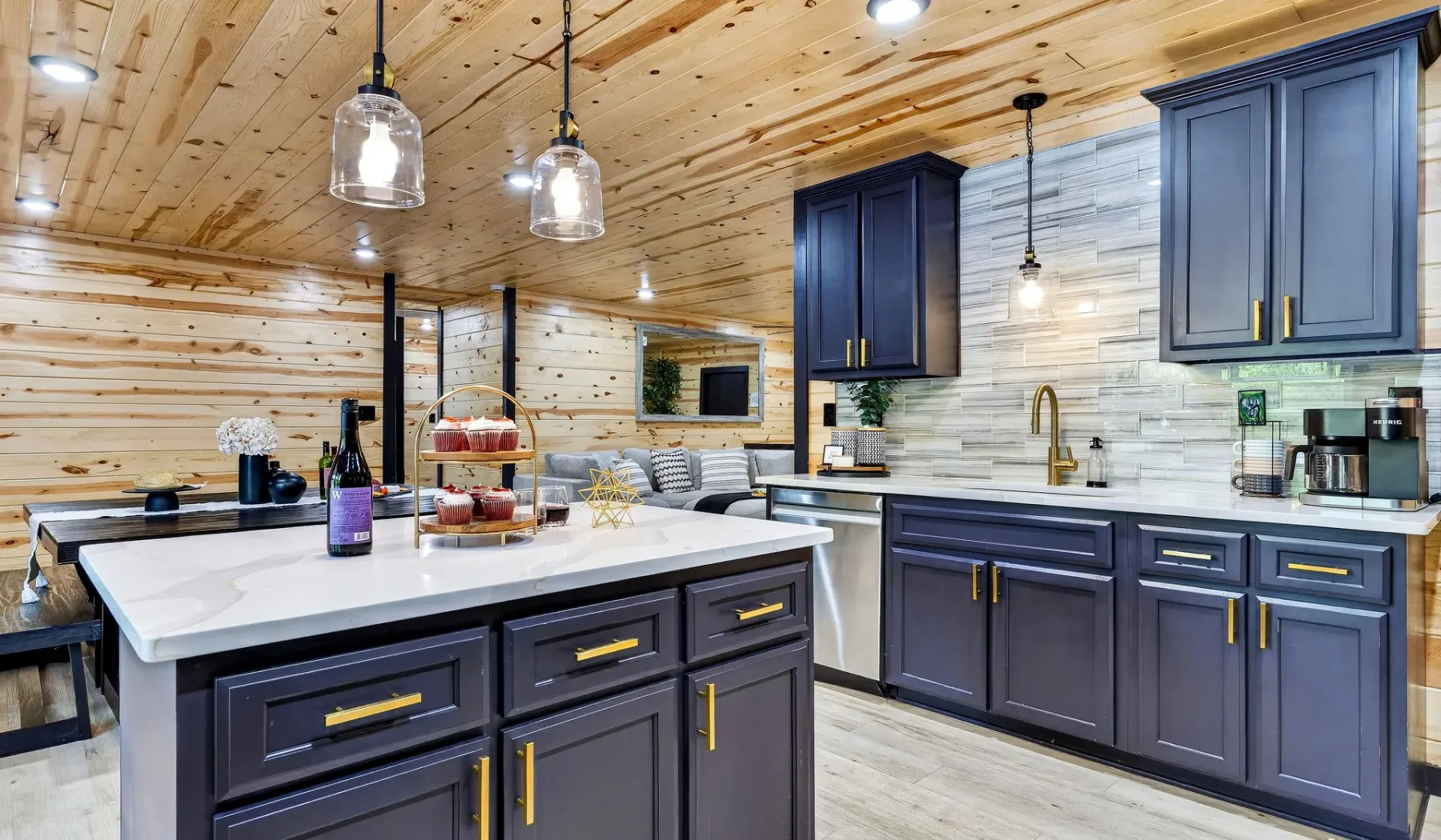 A kitchen with dark cabinetry, a large island, and light wood walls and ceiling.