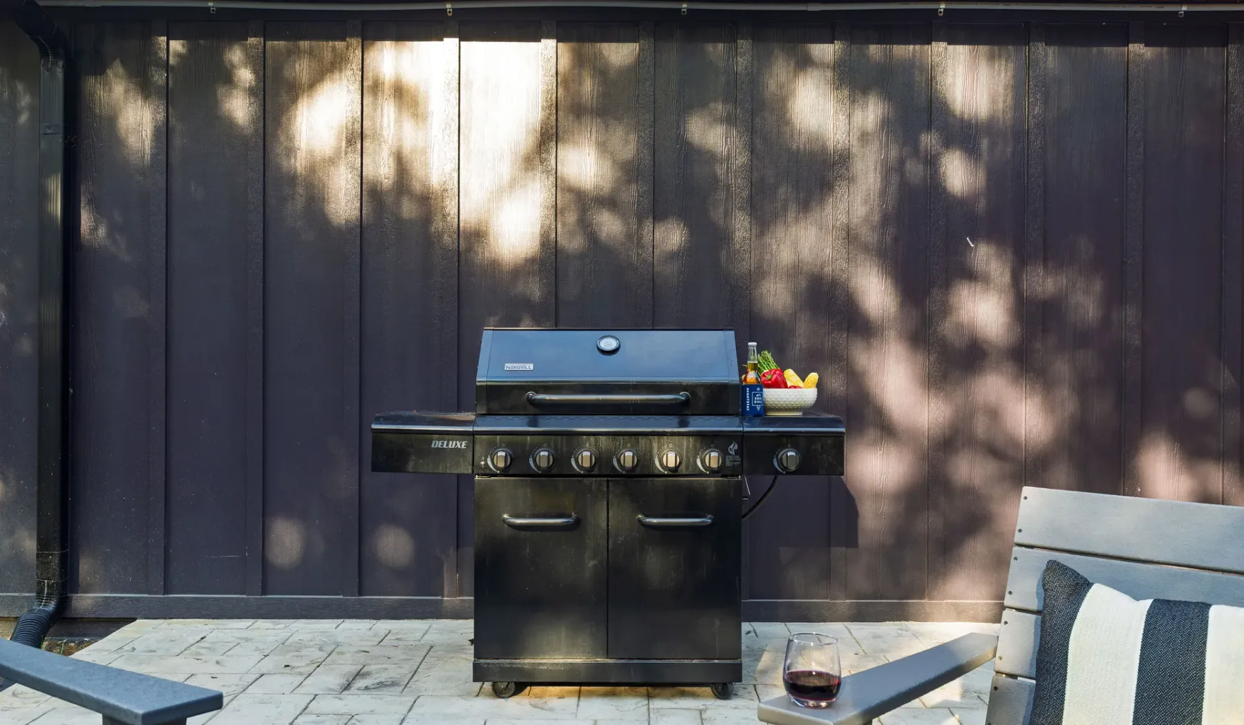 An outdoor cooking area features a grill beside patio seating.