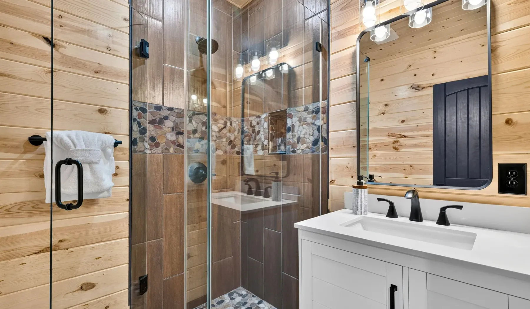 A bathroom with a glass shower and a white vanity.