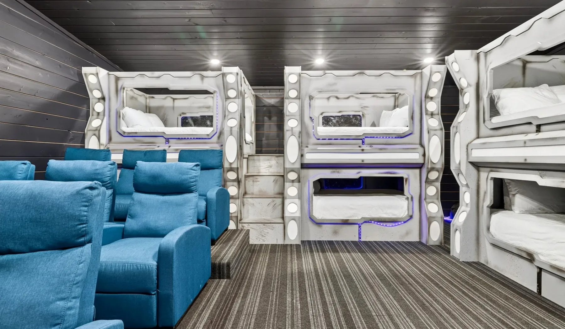 A compact sleeping area with blue seating and white built-in bunks.