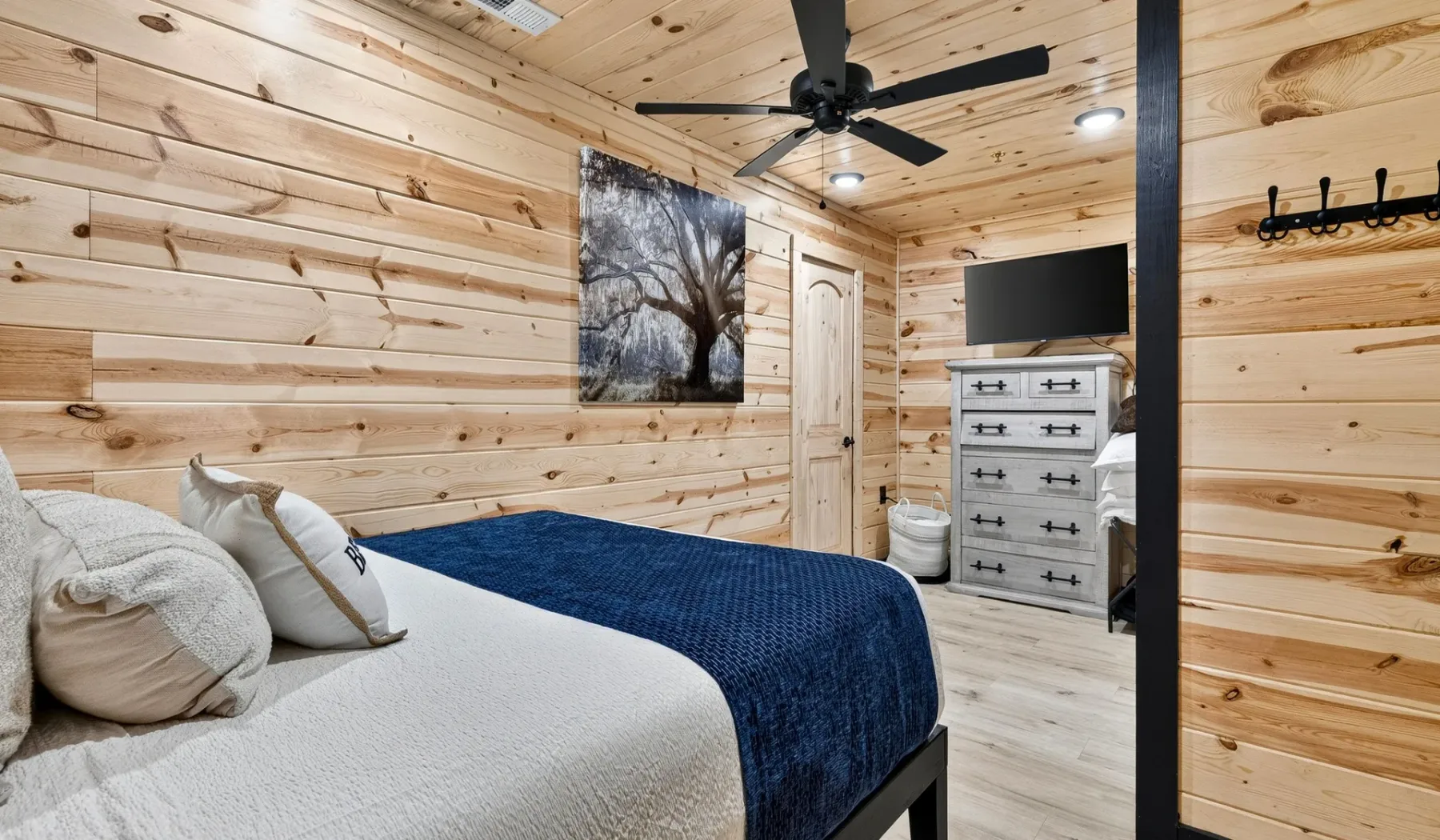 A bedroom with a bed, a dresser, and a ceiling fan.