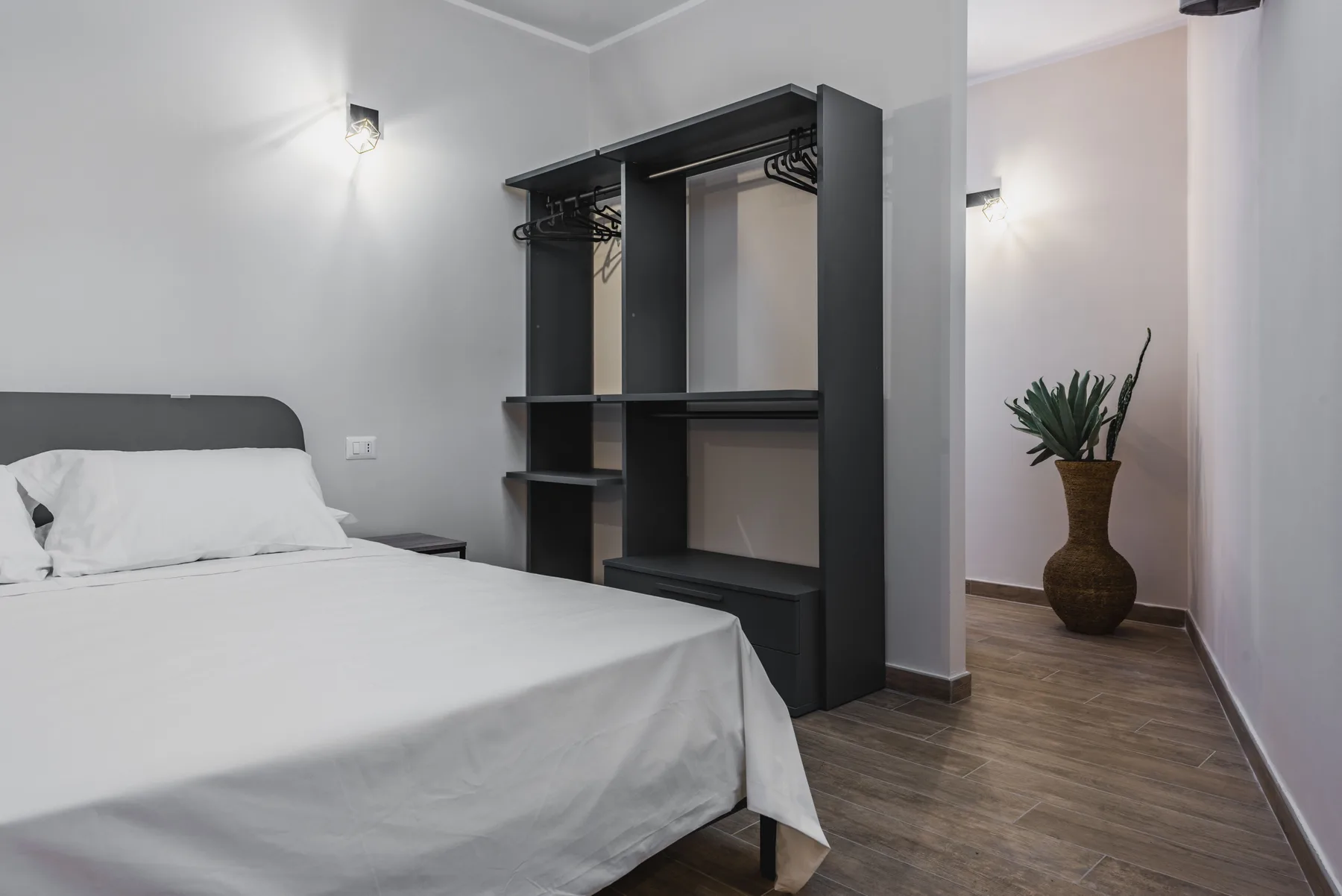 Un dormitorio con una cama bien tendida y un armario abierto.