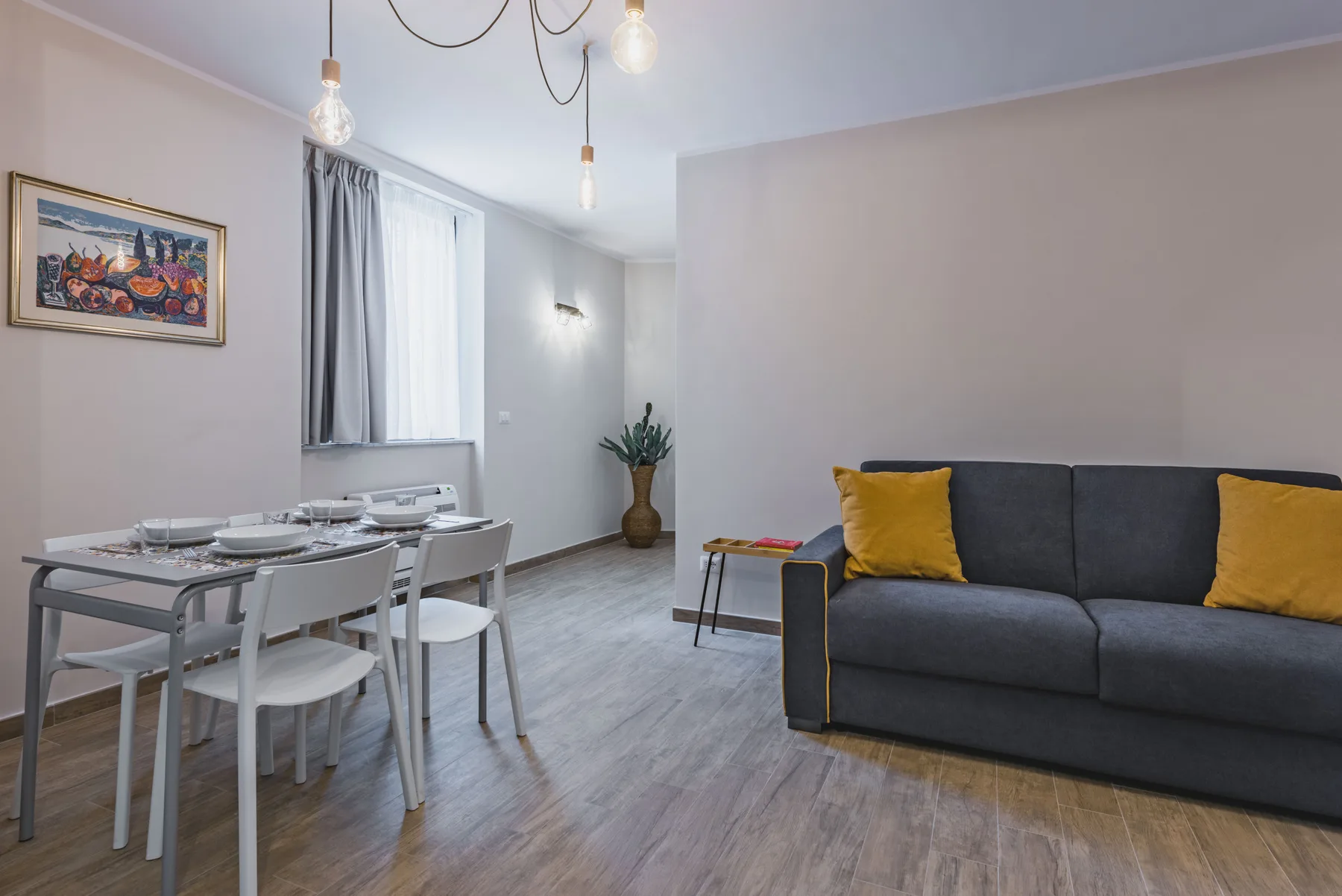 Una zona de estar y comedor con un sofá oscuro y una mesa preparada.