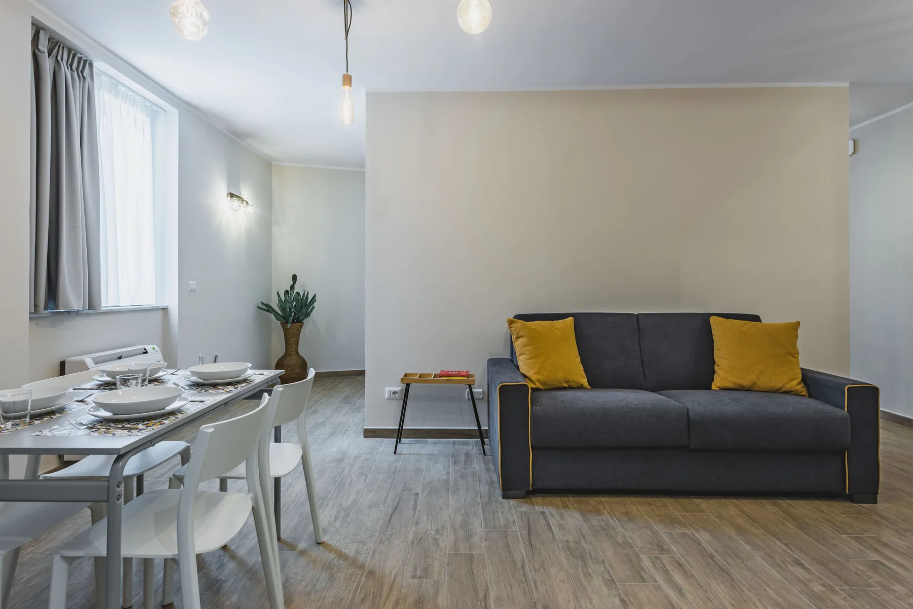 Una sala de estar y comedor con un sofá oscuro y una mesa puesta.