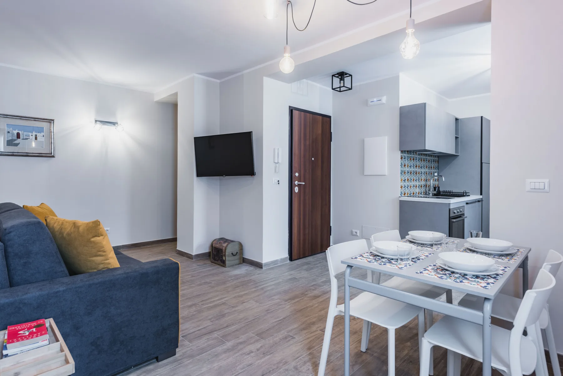 Una luminosa sala de estar y comedor con sofá, mesa y cocina compacta.