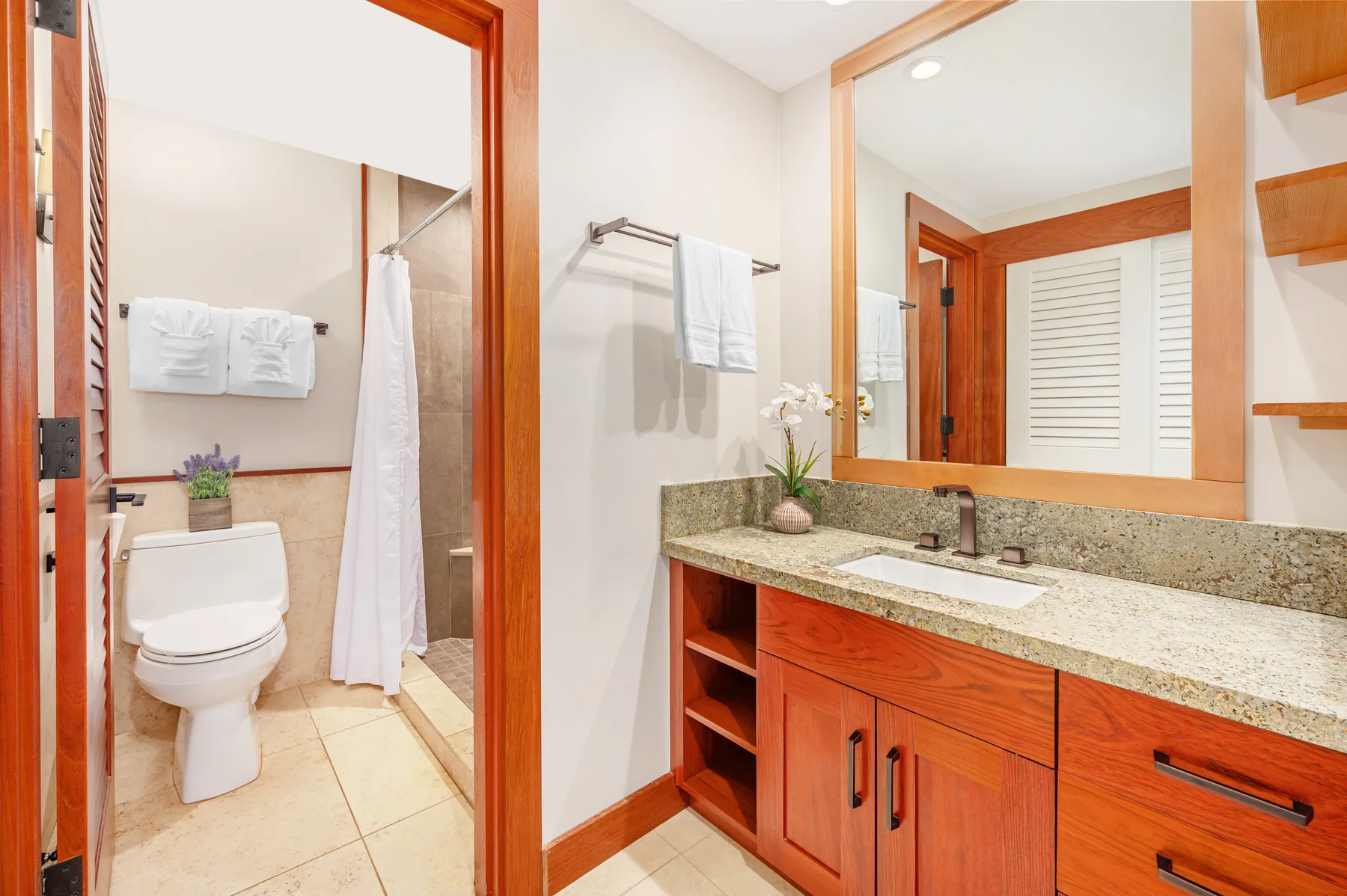 A bathroom vanity with a sink and mirror beside a toilet and shower.