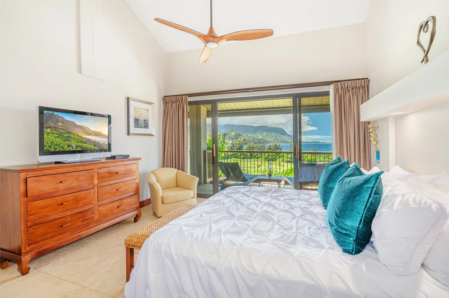 A bright bedroom with a bed beside sliding glass doors opening onto a balcony.