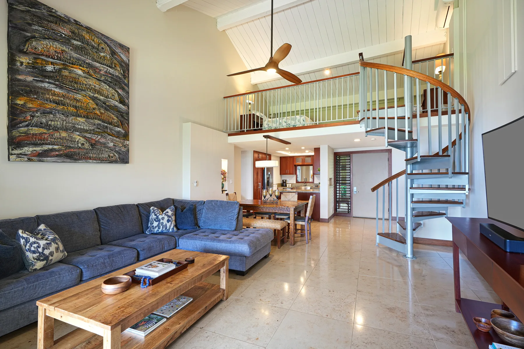 A living room with a sectional seating area and a staircase leading to an upper level.