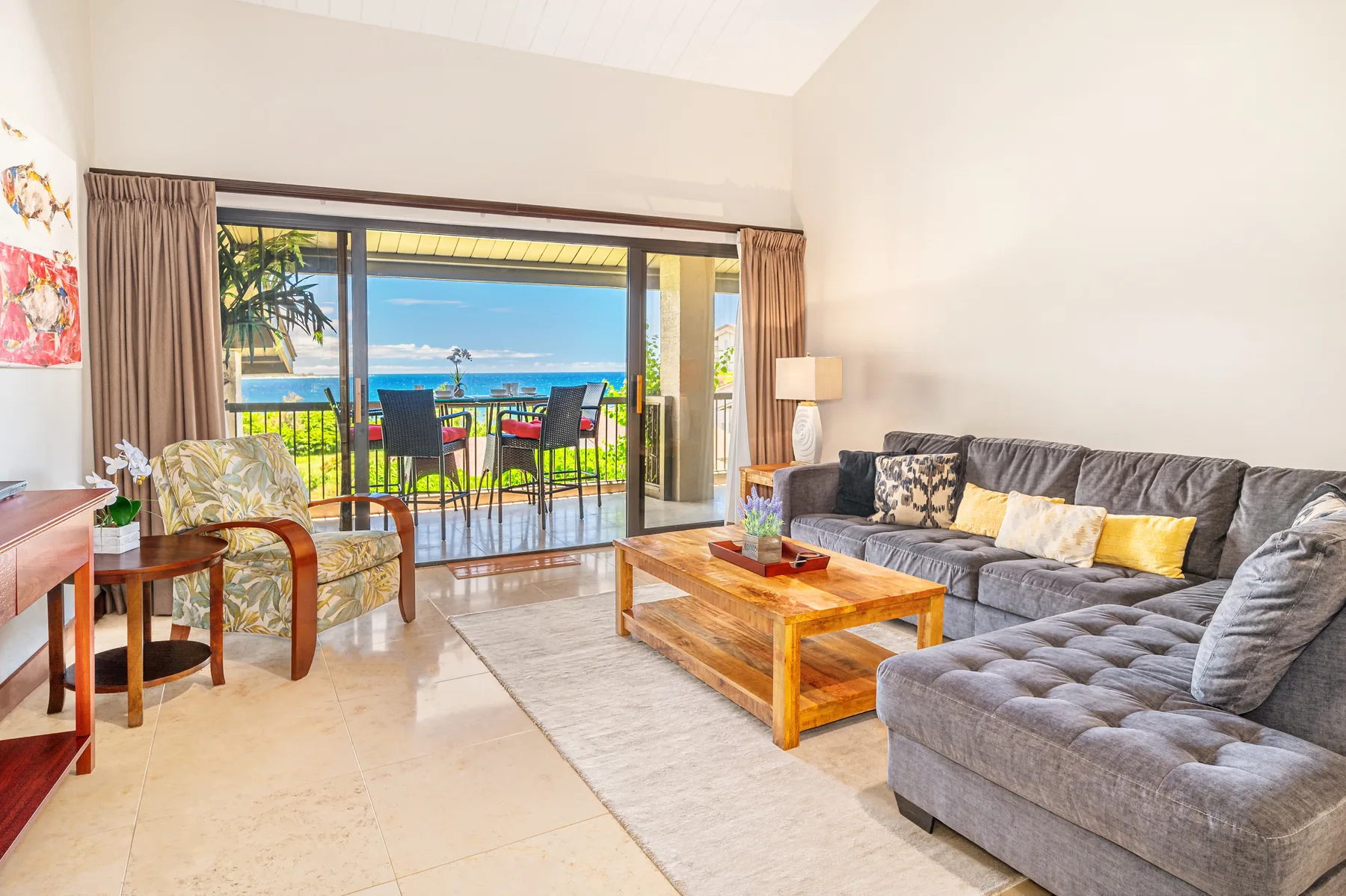 A bright living room opens onto a balcony with ocean views.